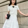O1CN01vzwzQw1MQX6ust4lo_513051429.jpg_q50.jpg_.webp 乐町miu系通勤珍珠白巧针织短袖套装裙夏新款蝴蝶结细麻花翻领T恤